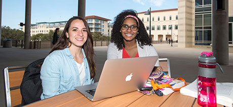 Two students outdoors on a laptop