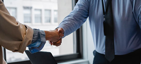 Two people shaking hands over a desk