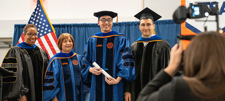 Photographer taking photos of doctoral graduate with Graduate School Deanuate with 